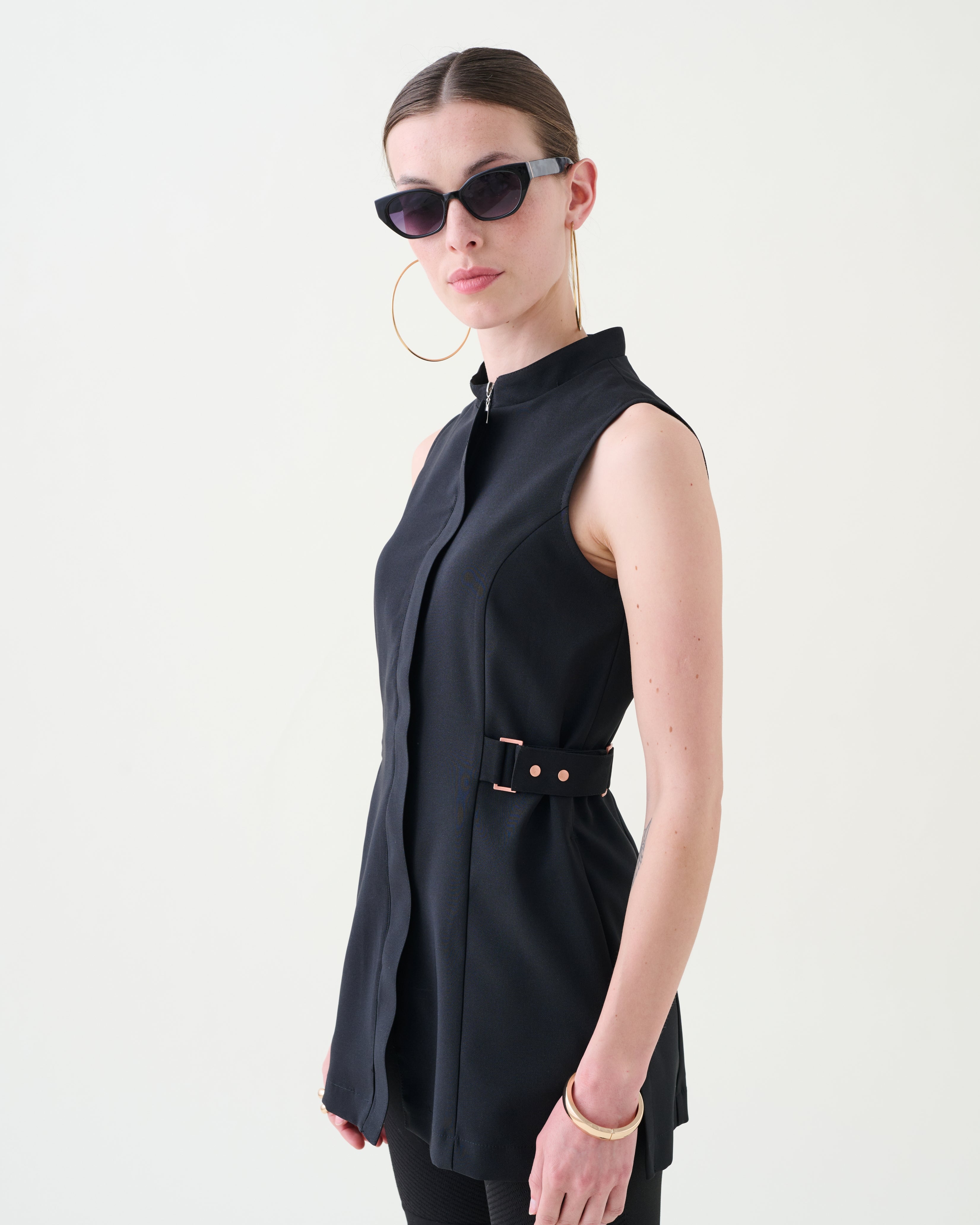 Woman wearing a black sleeveless dress with a belt on a white background from the Buttercups uniforms collection
