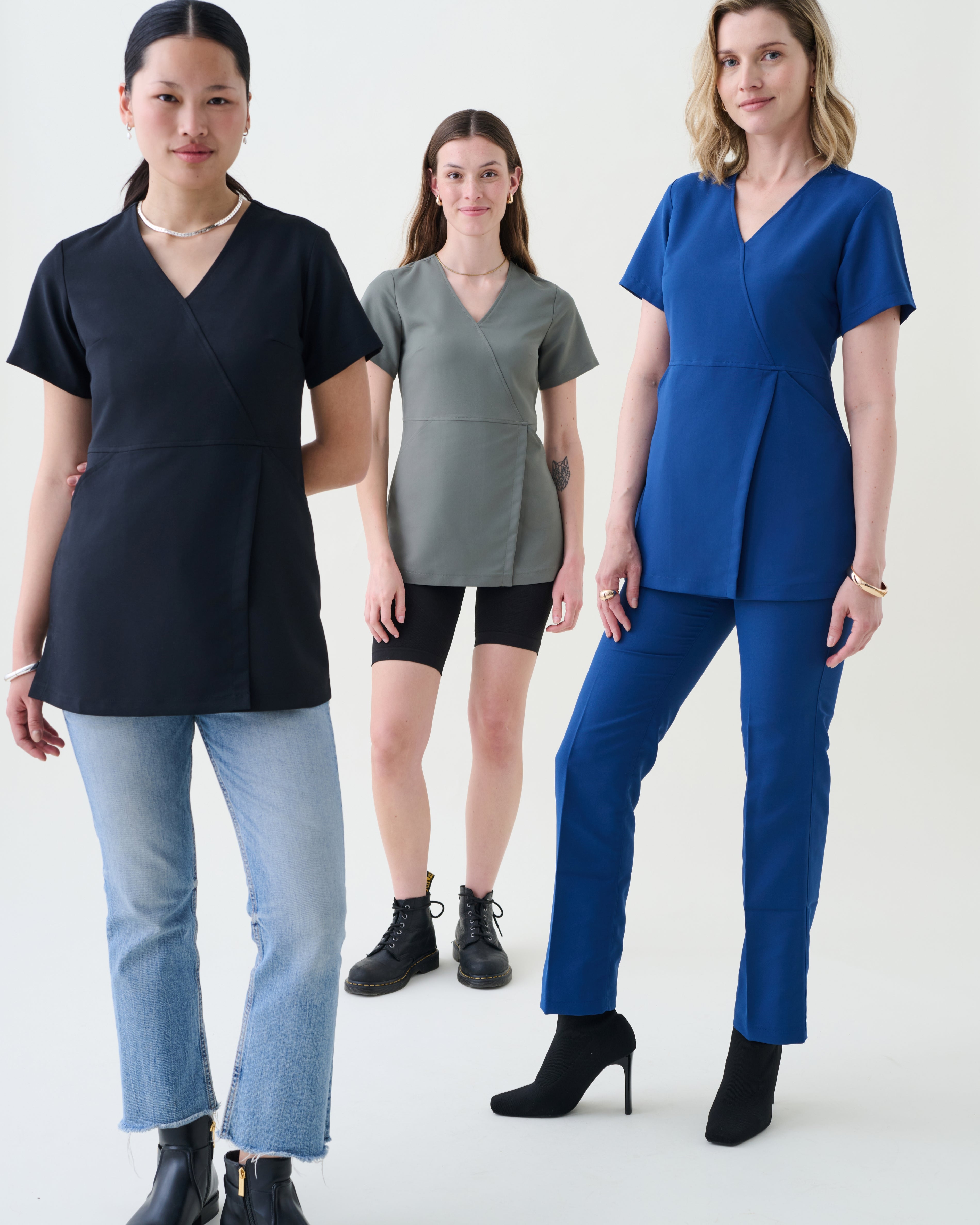 Three women wearing different colored scrub sets on a white background