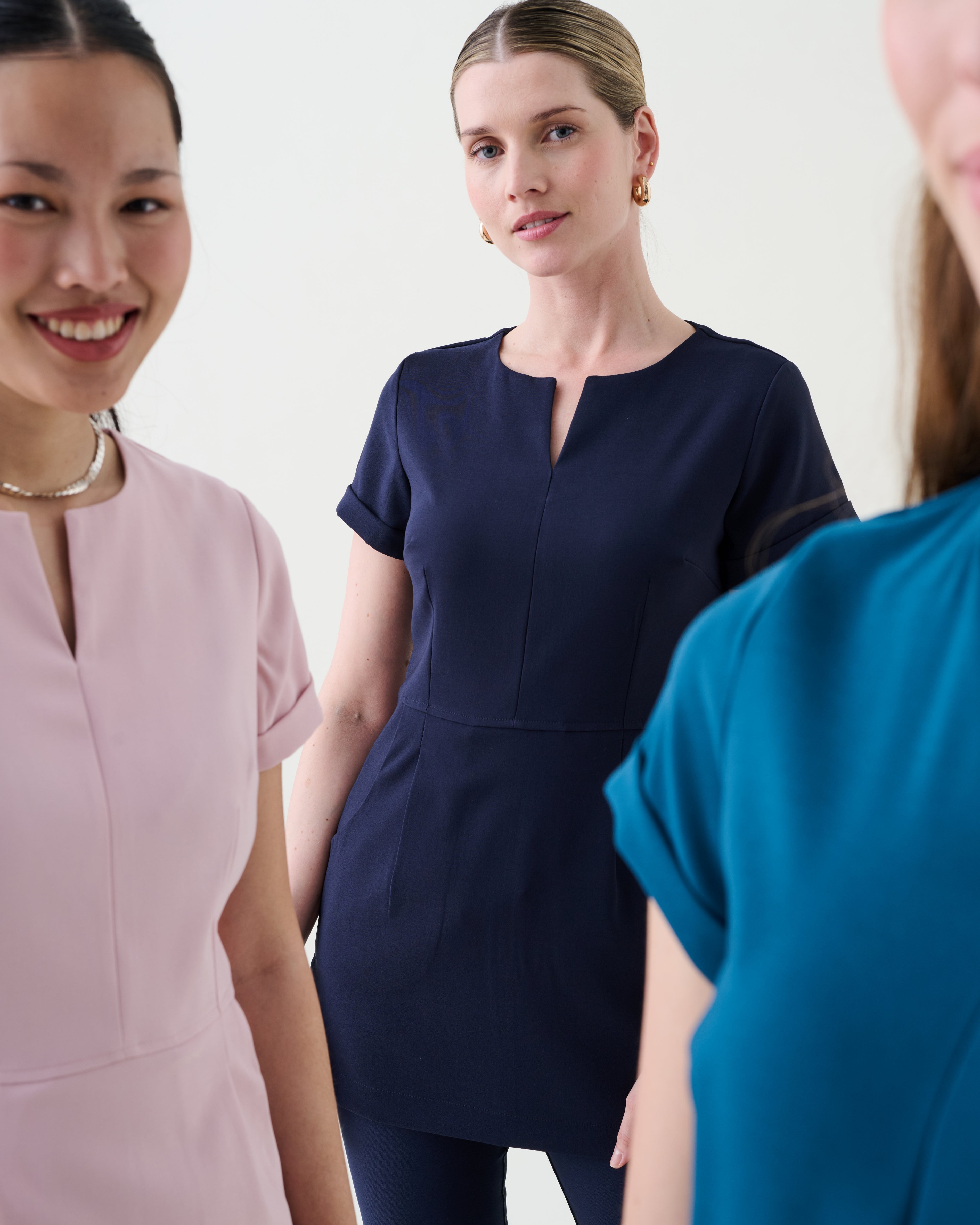 Zoomed in three women wearing different coloured beauty uniforms