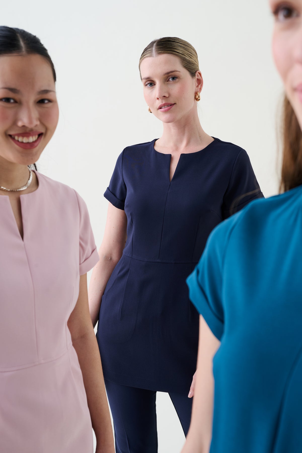 Zoomed in three women wearing different coloured beauty uniforms