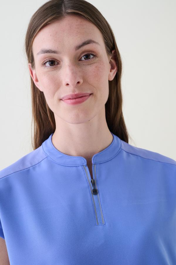 Woman wearing a blue shirt with a zipper from the healing hands collection