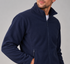 A man wearing a navy blue fleece zip-up jacket, shown from the chin down against a plain light gray studio background.