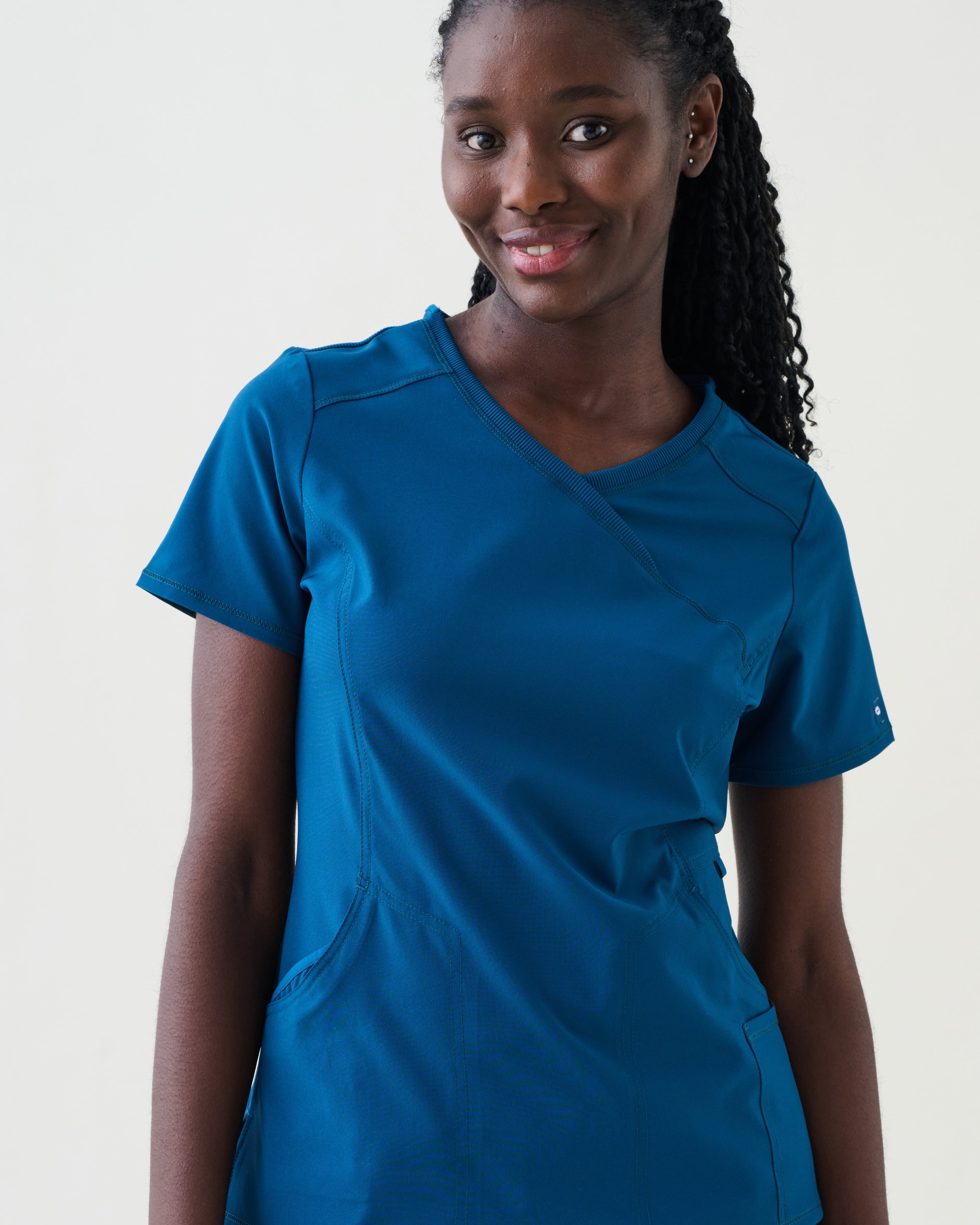 Person wearing a blue scrub top and pants on a plain background